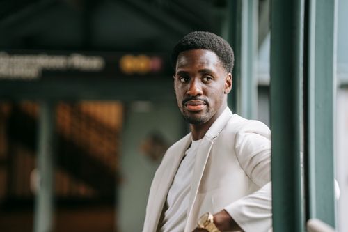 Free Confident black man in fashionable attire posing at an urban station with modern elegance. Stock Photo
