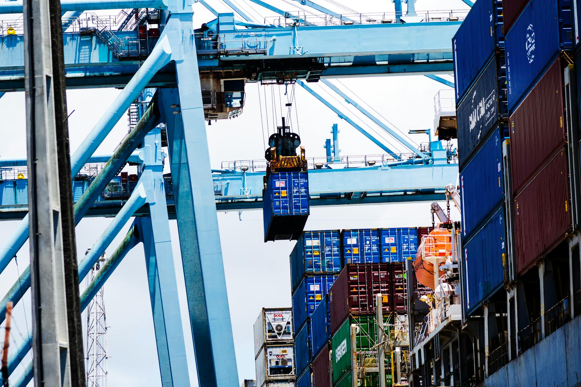 Cargo cranes lifting shipping containers at a bustling industrial port.