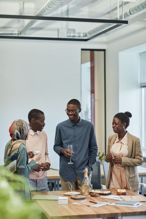 Free Four colleagues at a relaxed office gathering enjoying snacks and drinks. Stock Photo
