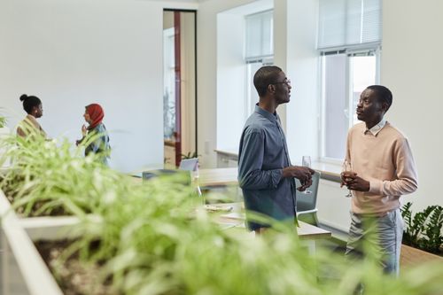 Free Business colleagues enjoy a casual conversation over drinks in a contemporary office setting. Stock Photo