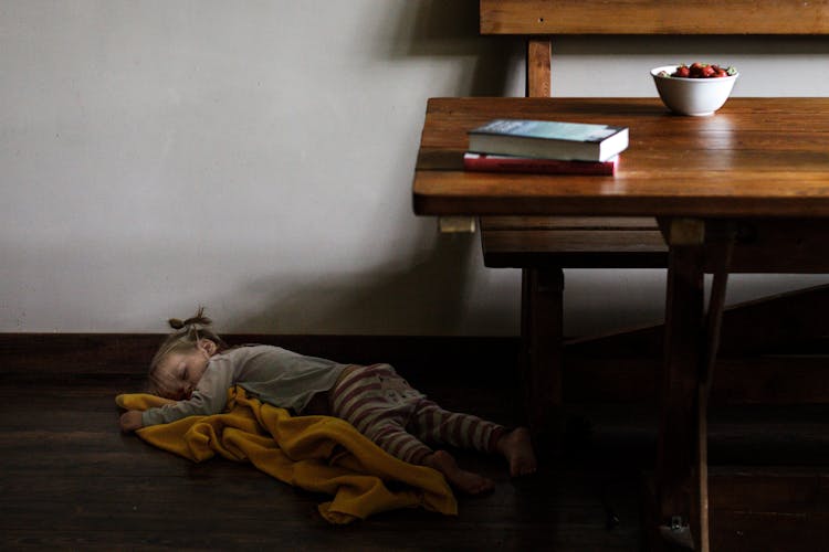 Young Girl Sleeping On Wooden Floor