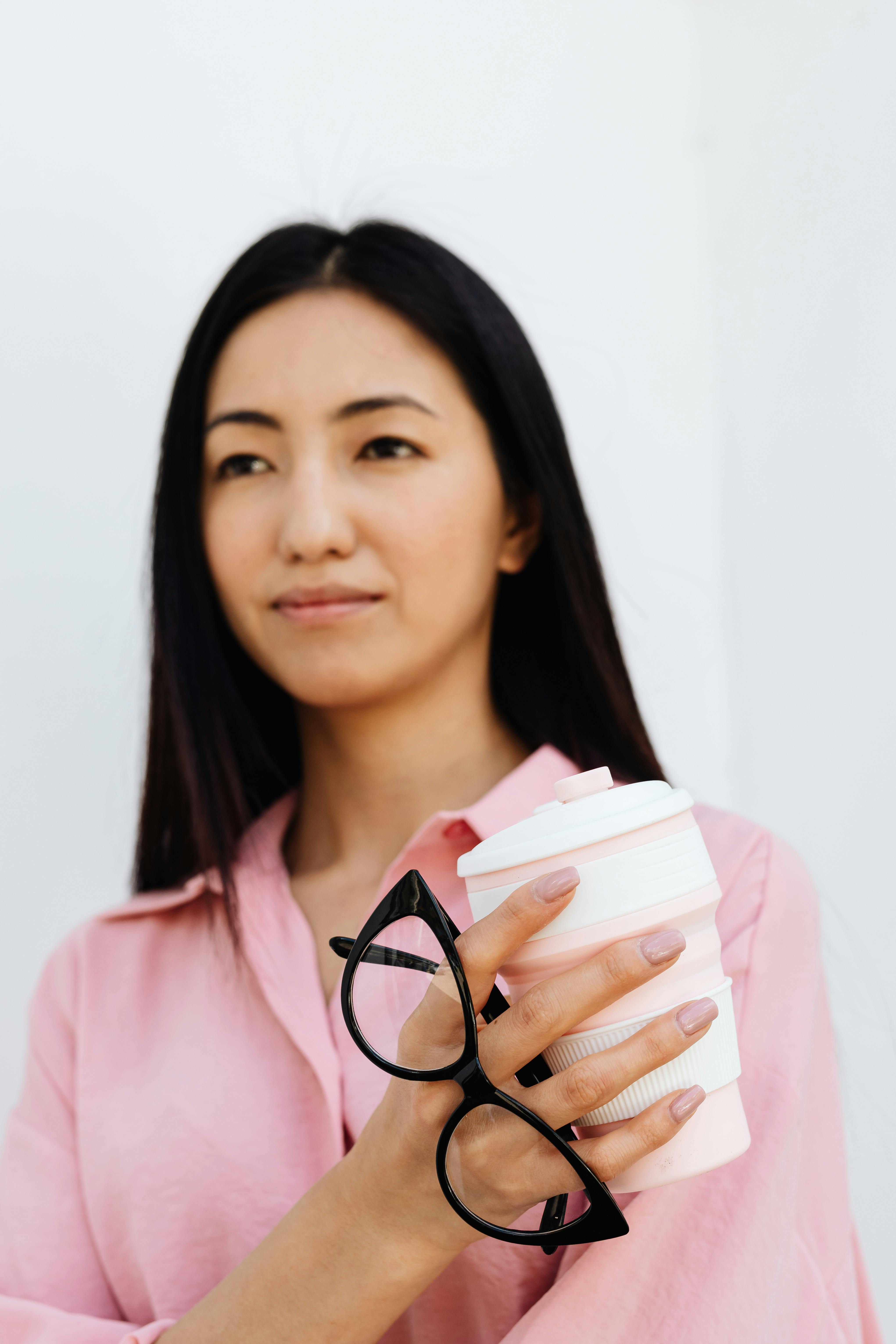 woman holding cup and eyeglasses