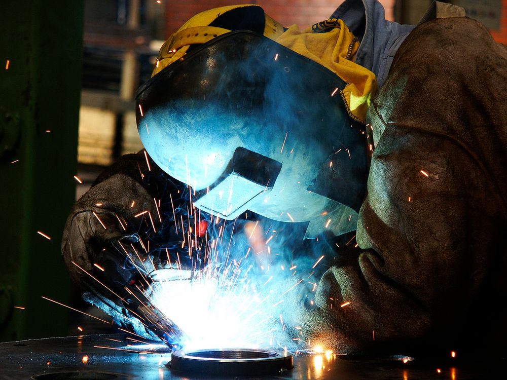 Welder joining beams on a structural steel framework as sparks fly