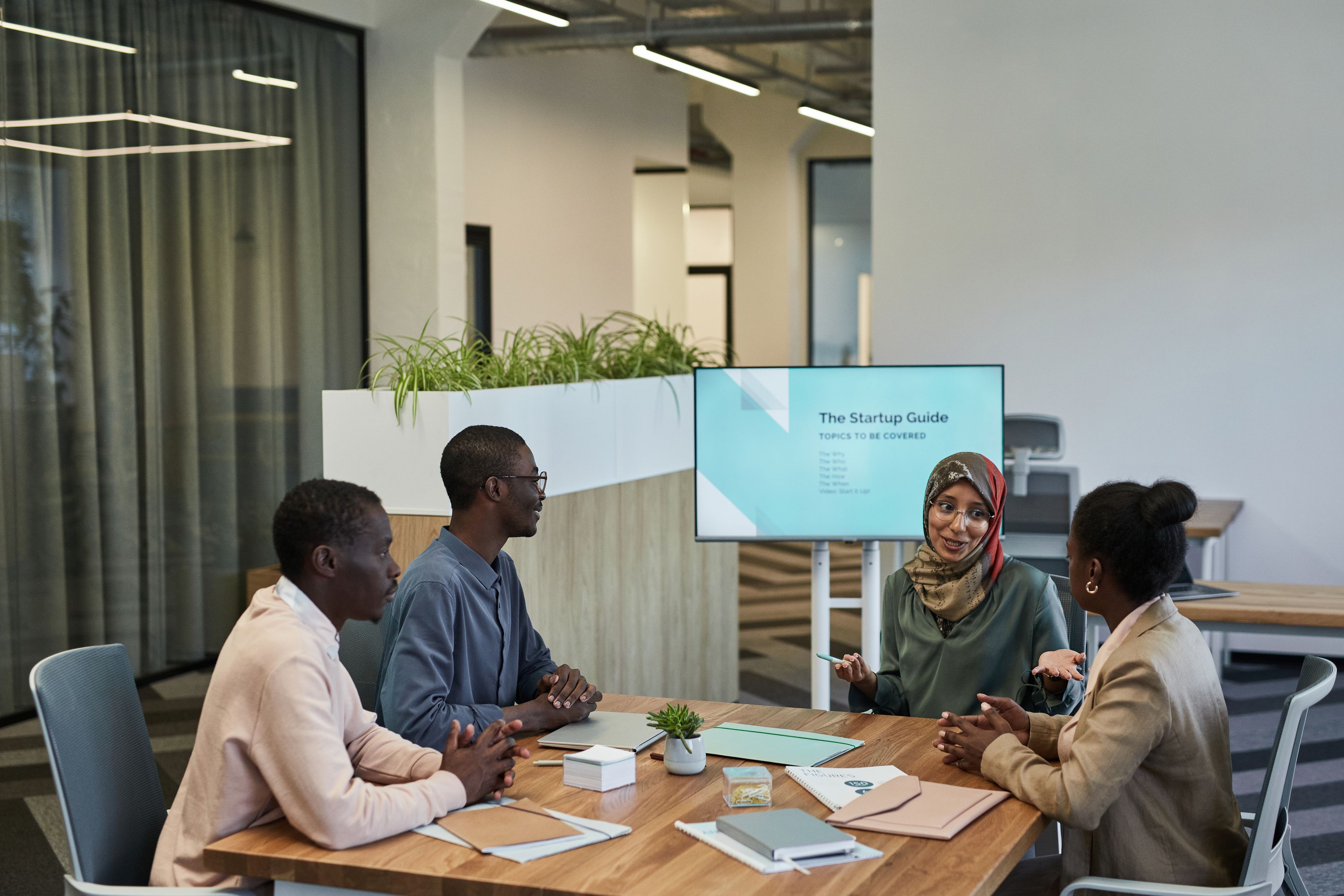 A diverse team discussing a startup guide in a modern office space, focusing on collaboration.