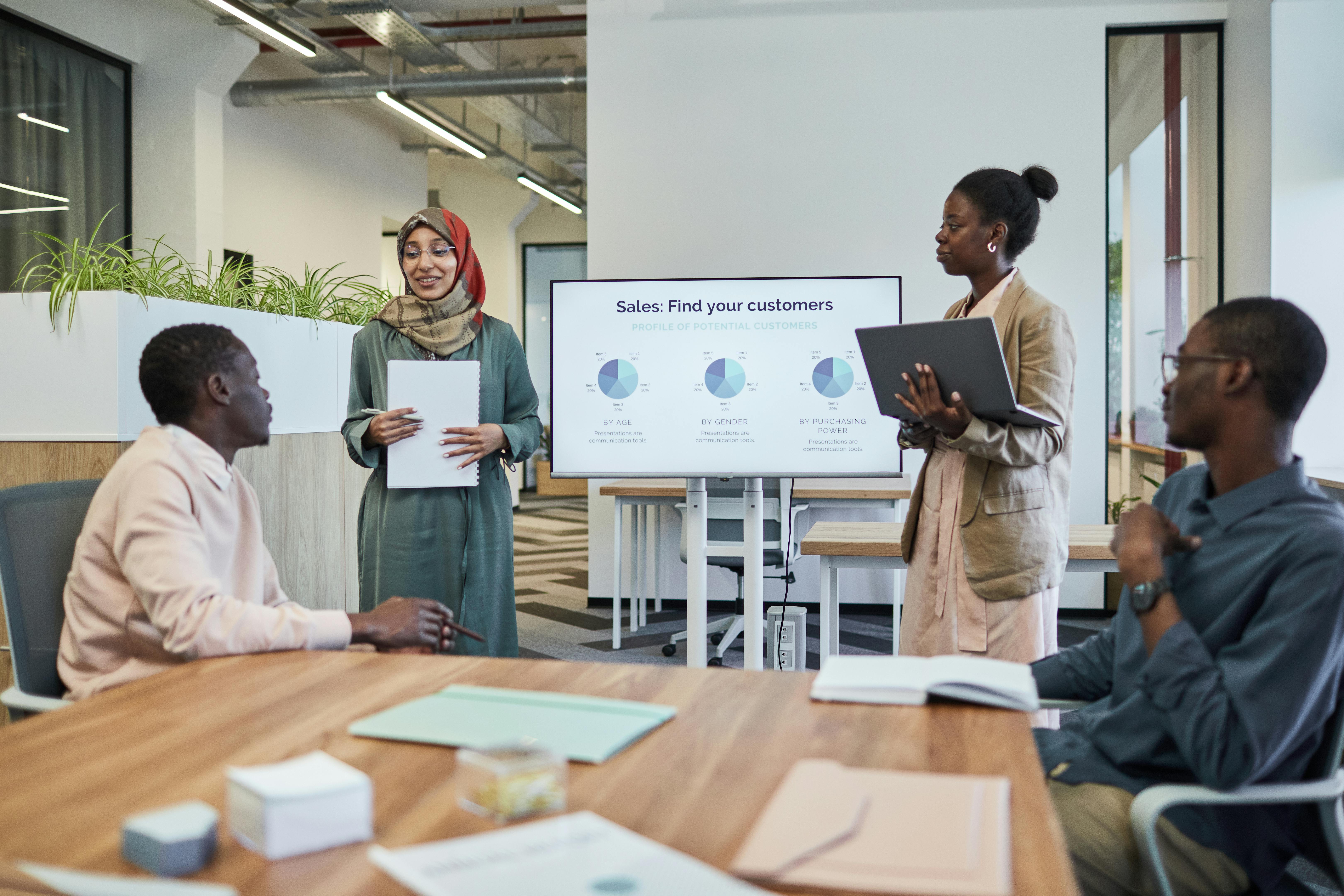 A diverse team discusses business strategy during an indoor presentation.