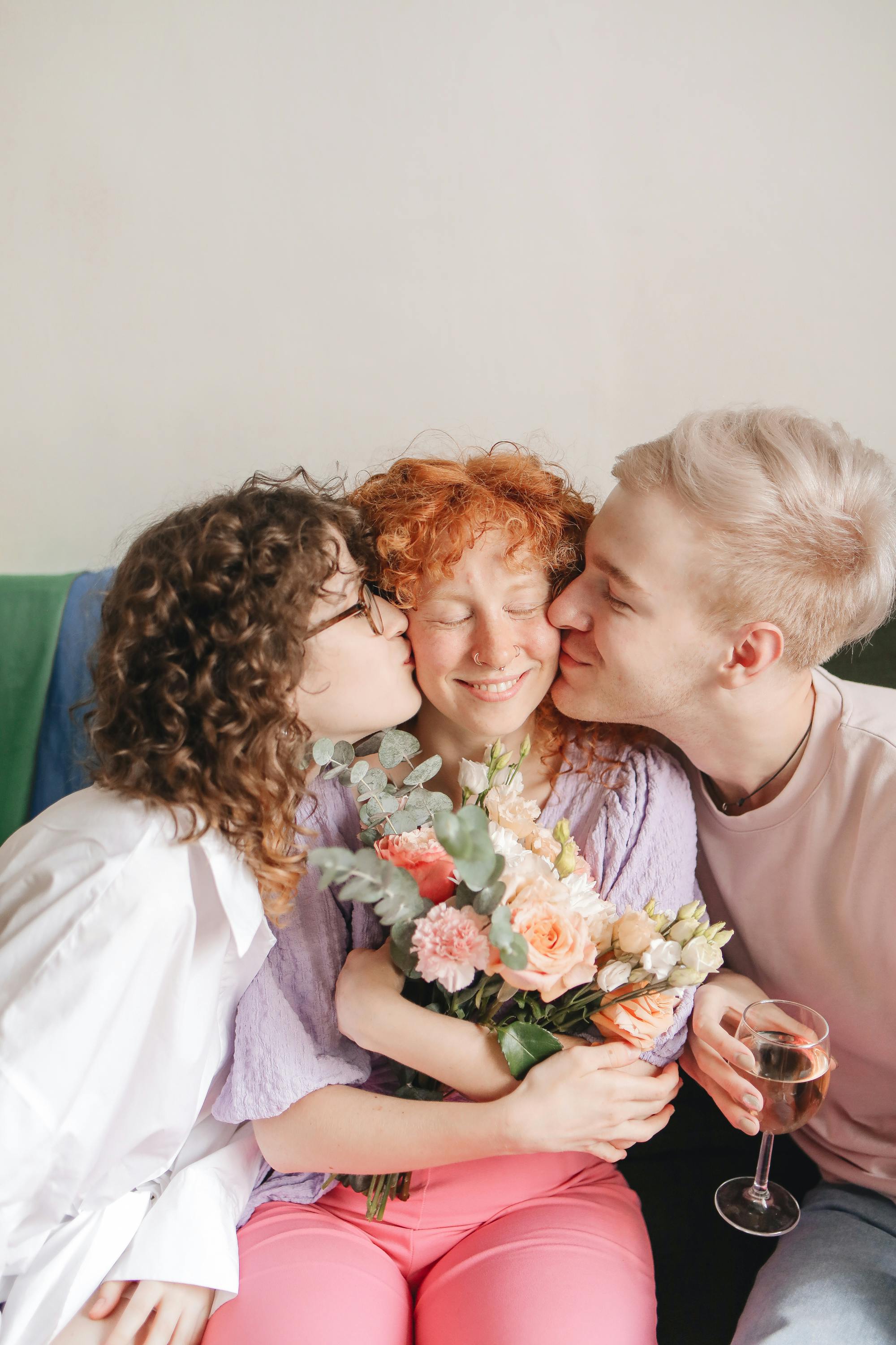 Friends sharing affectionate moments, giving hugs and flowers indoors.