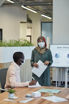 Professional business meeting with masks and social distancing in an office setting.