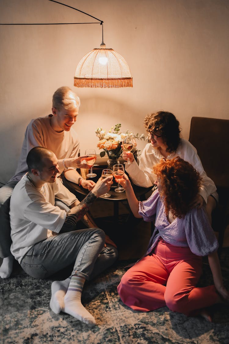 Group Of Friends Clinking Glasses Of Wine While Sitting At Home 