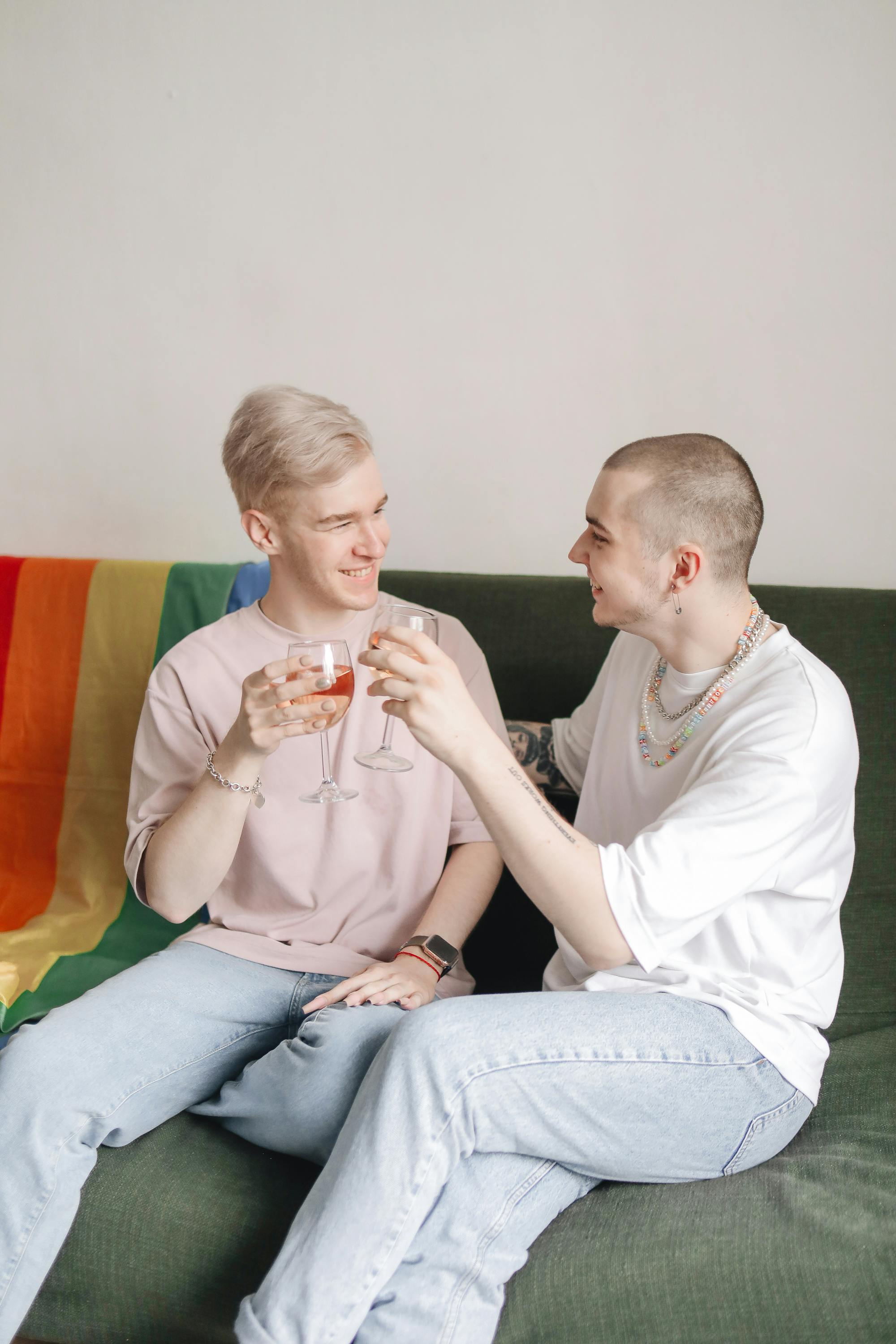 a same sex couple sitting on a couch while holding a wine glass