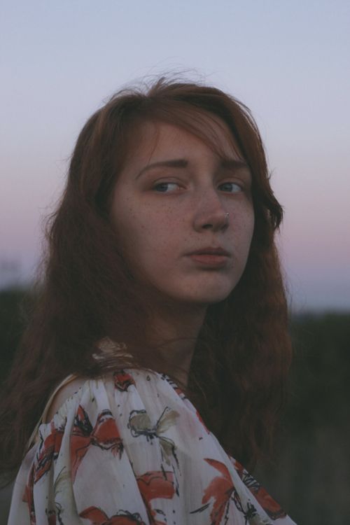 Free Woman with long hair gazing thoughtfully during twilight outdoors, creating a moody atmosphere. Stock Photo