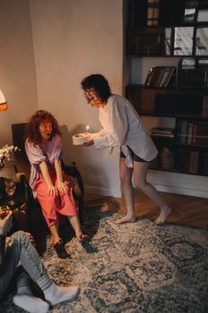 Two women celebrating indoors with a small cake and candle, creating a warm and intimate atmosphere.