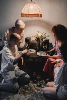 A warm celebration with friends sharing a cake indoors under ambient lighting.