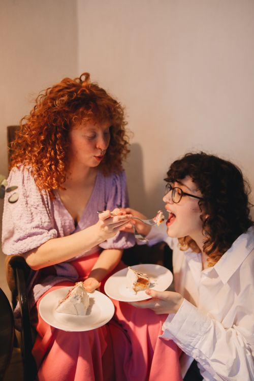 Free Two women share cake in a warm setting, celebrating together indoors. Stock Photo