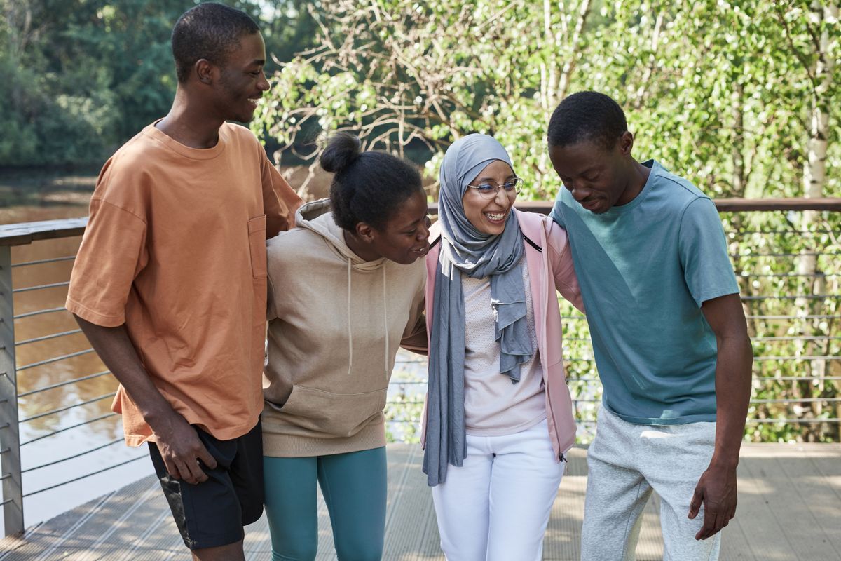 A group of friends laughing and embracing each other outdoors
