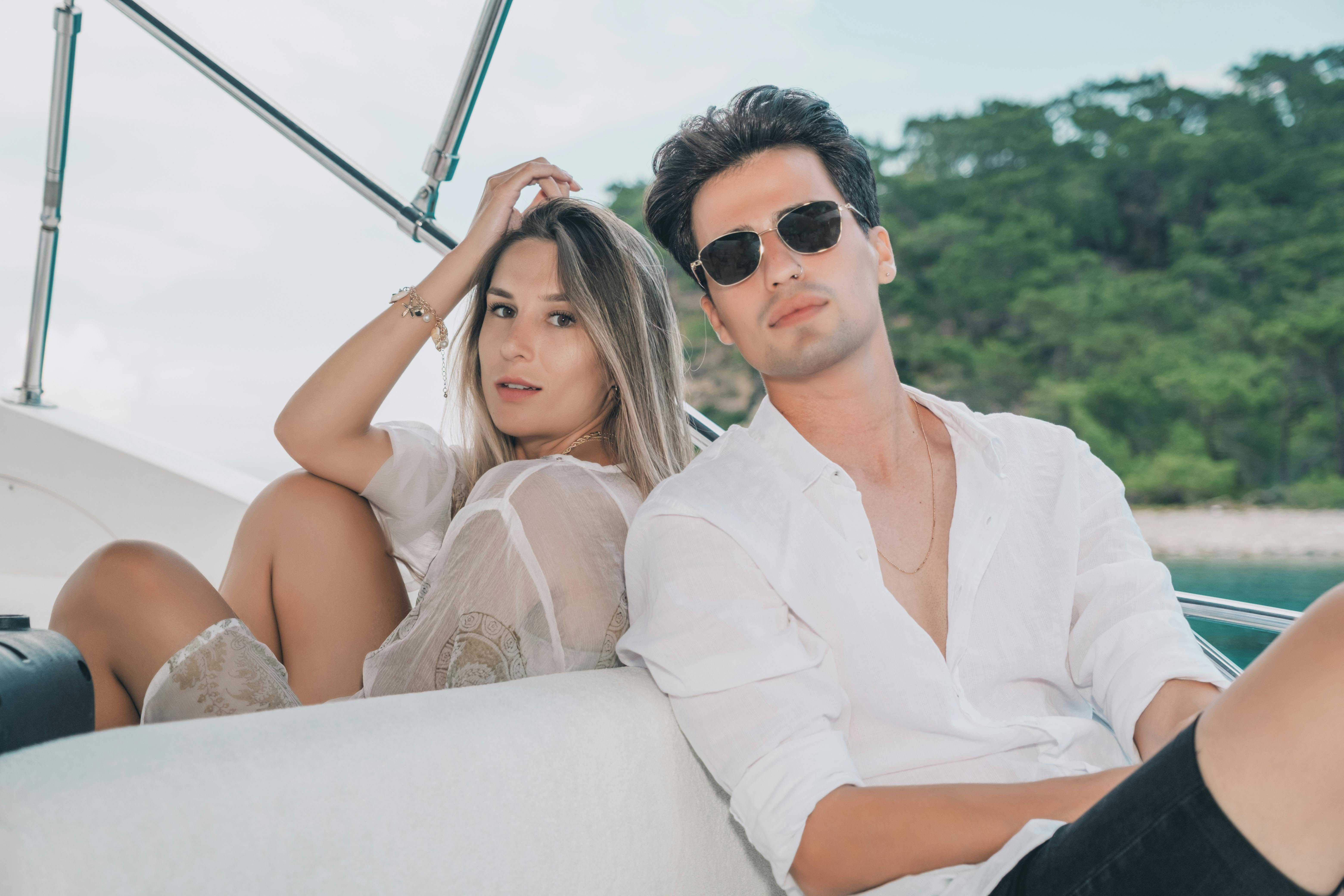 a handsome man and beautiful woman sitting on a yacht