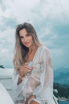 Chic woman in a white dress sipping champagne on a yacht in Antalya.