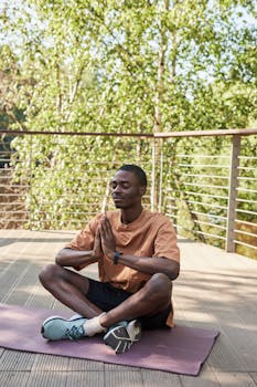 A young man meditating on a yoga mat outdoors, exuding calm and relaxation.