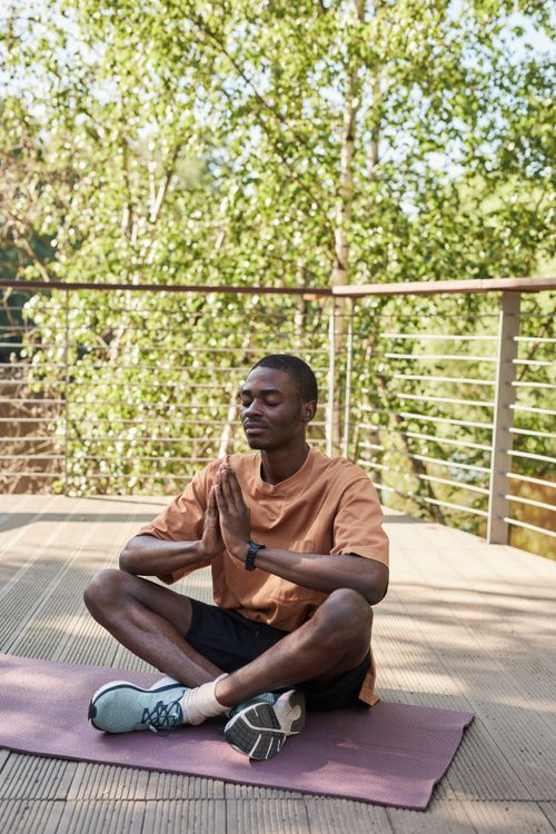 Free A young man meditating on a yoga mat outdoors, exuding calm and relaxation. Stock Photo