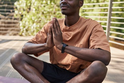 Free Man practicing yoga outdoors, sitting cross-legged in meditation pose. Stock Photo