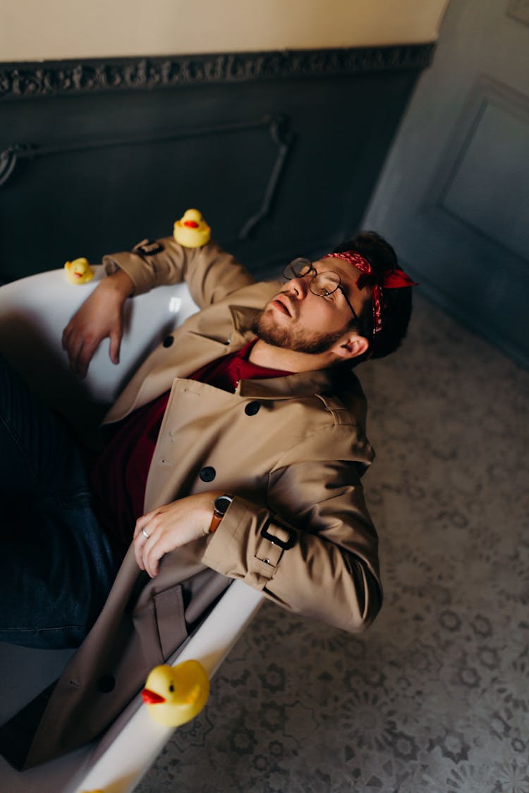 Man In Coat In Bathtub With Toy Ducks