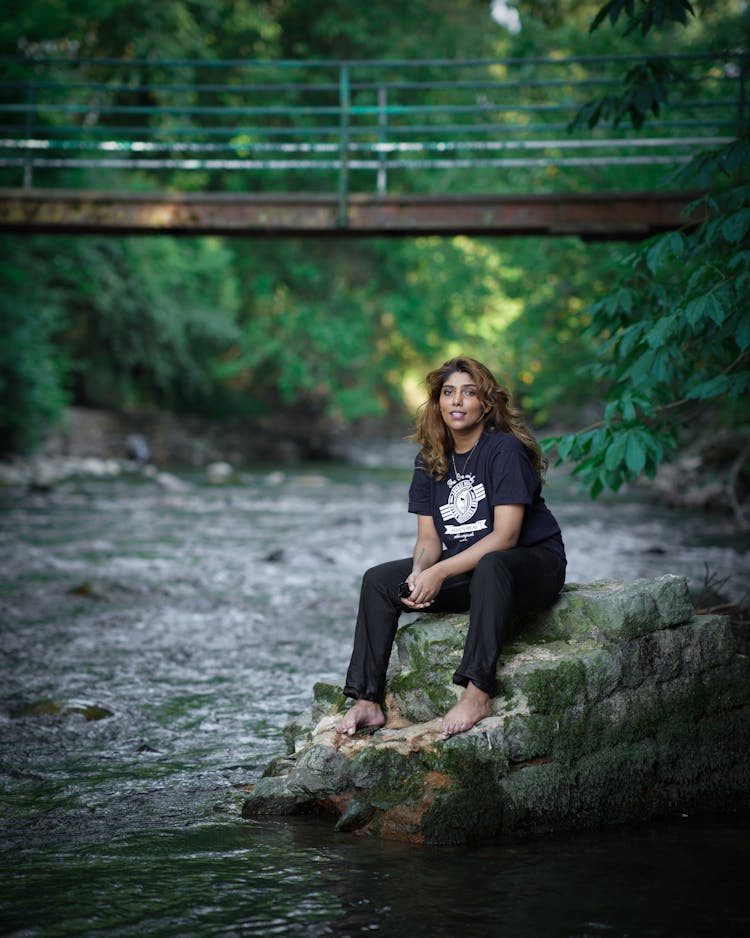 Woman In Black Shirt And Pants Sitting On Rock