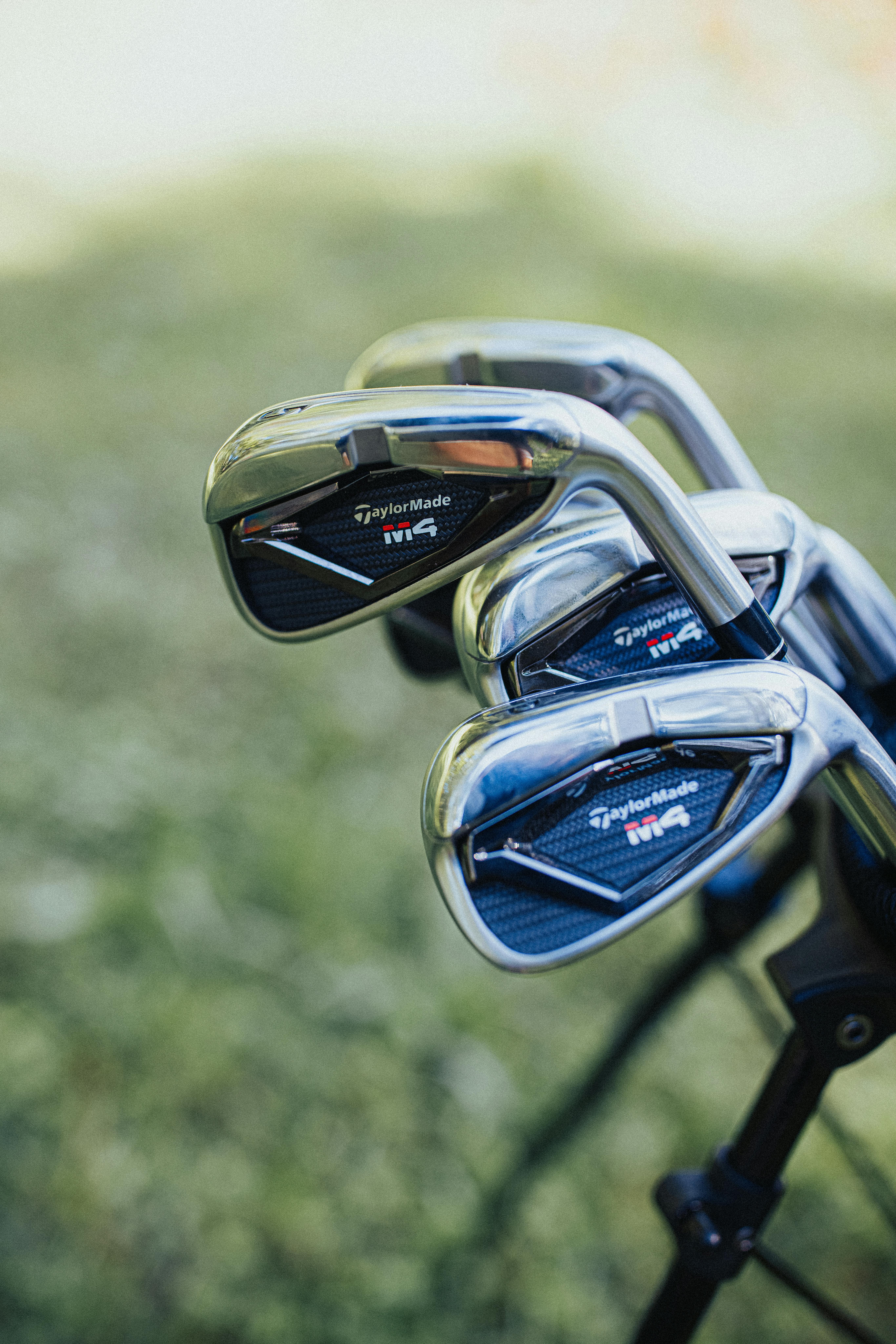 Close-up view of golf clubs with blurred background outdoors.