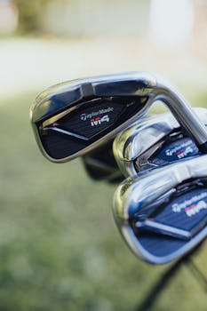 Macro shot of shiny golf clubs with a blurred background outdoors.