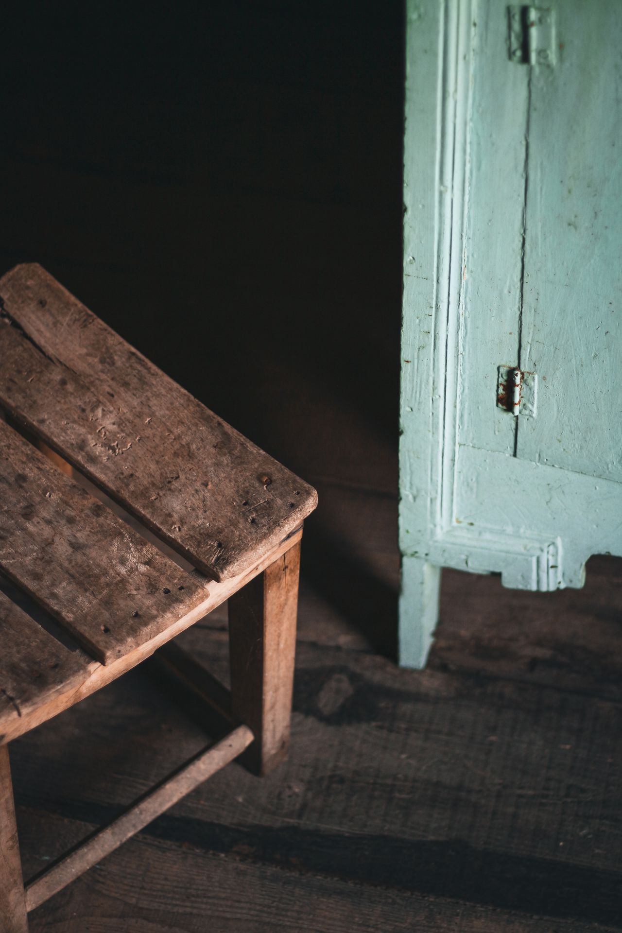 Rustic wooden chair beside a mint-green painted cabinet