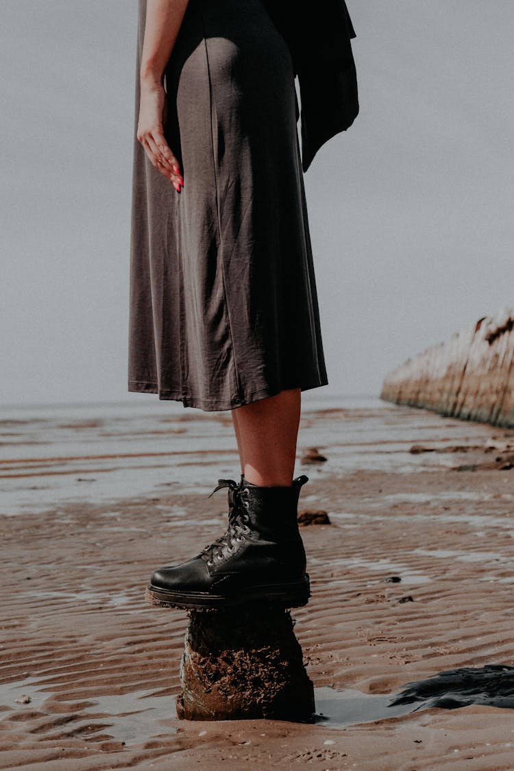 Woman In Black Dress Wearing Boots Standing On Rock 