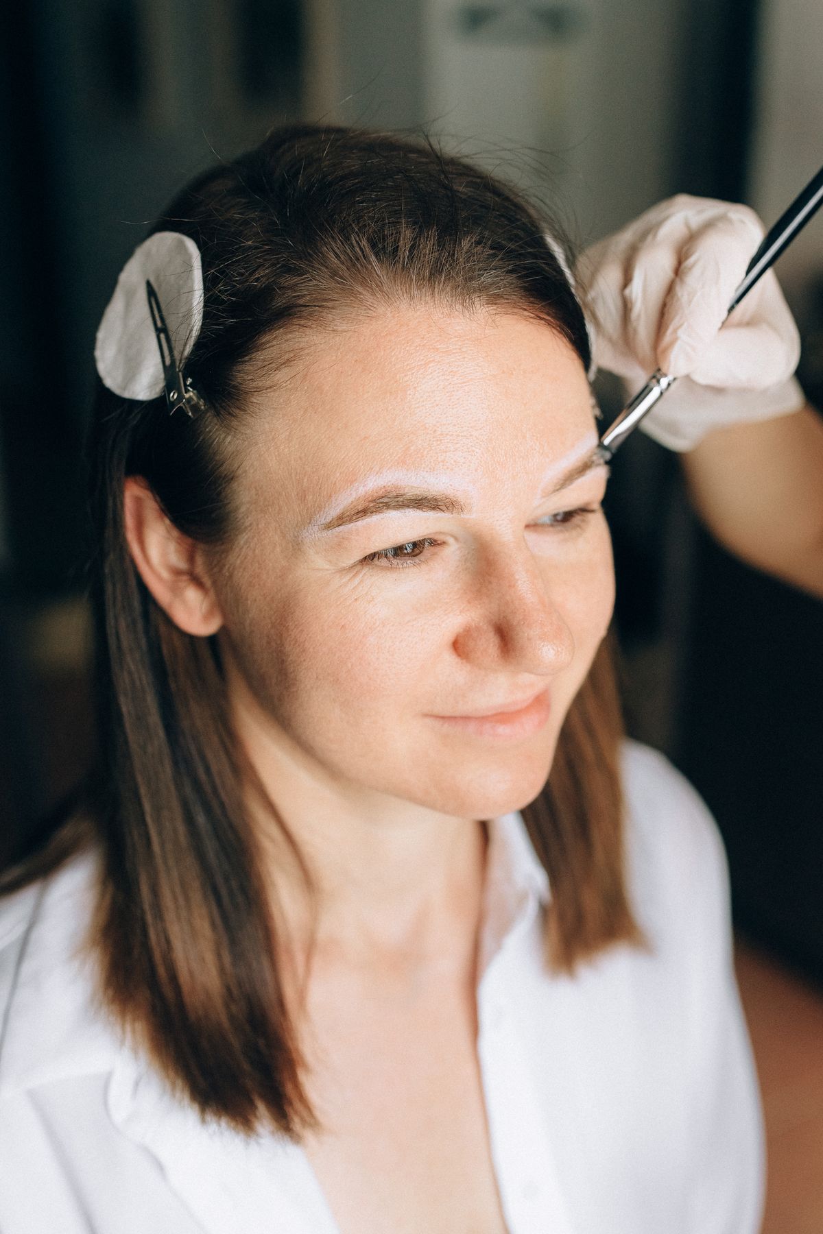 Woman having her eyebrows shaped with a makeup brush and pomade
