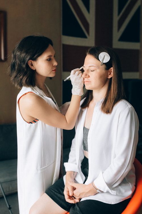 Free A makeup artist applying cosmetics on a woman's face, showcasing professional beauty techniques indoors. Stock Photo