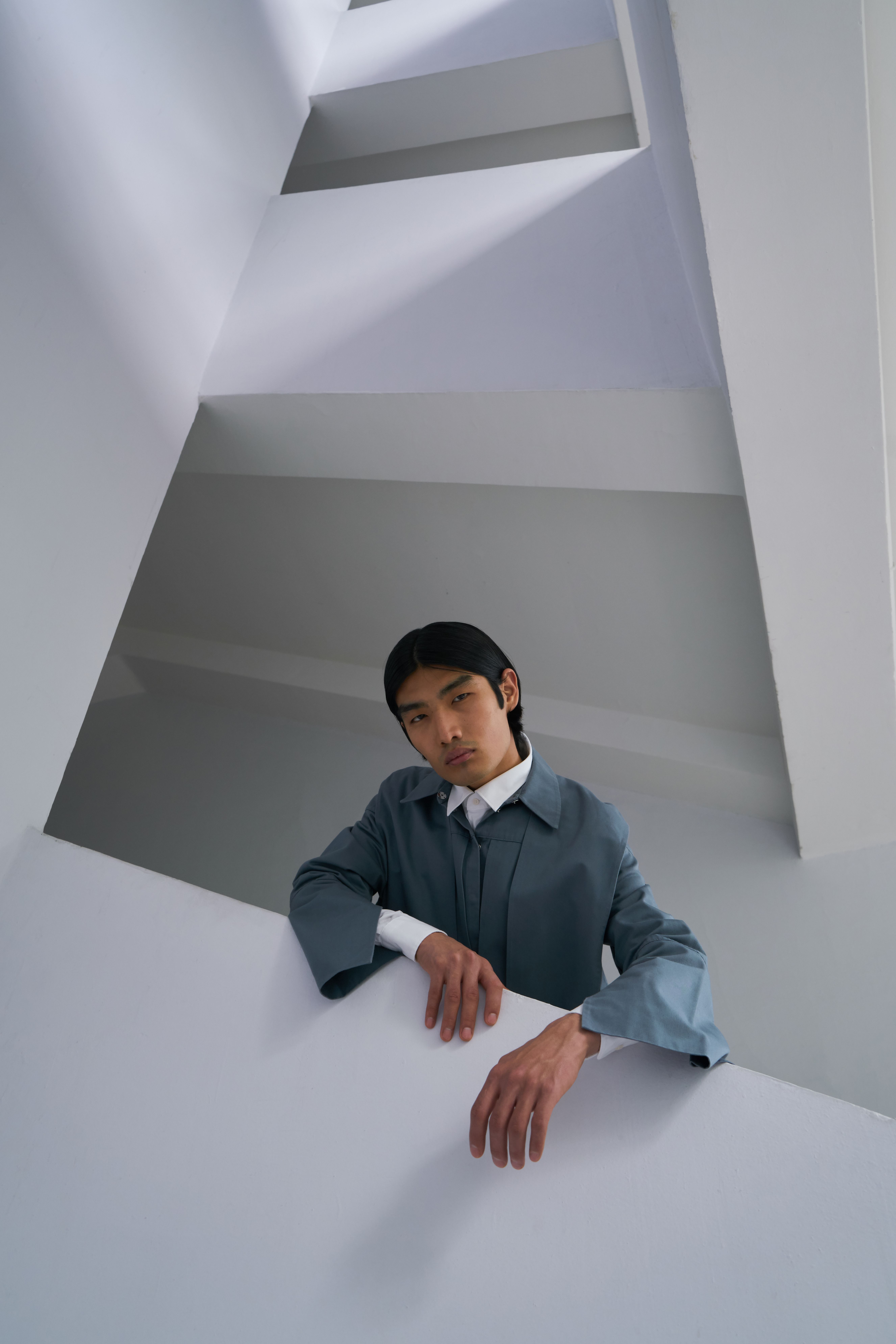 Stylish portrait of a male model in a modern, geometric interior with white walls.