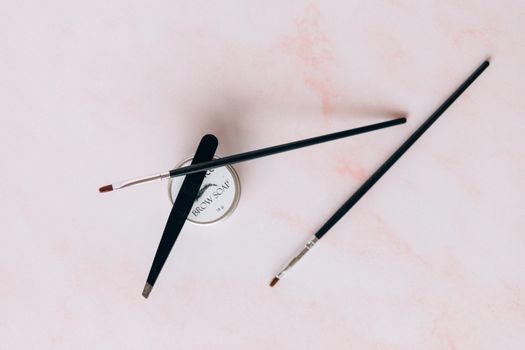 Tweezer, Make-up Brushes and Brow Soap on a Pink Surface