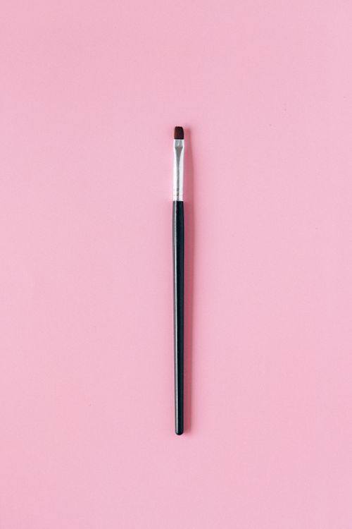 Free High-quality image of a makeup brush on a pastel pink background for beauty themes. Stock Photo