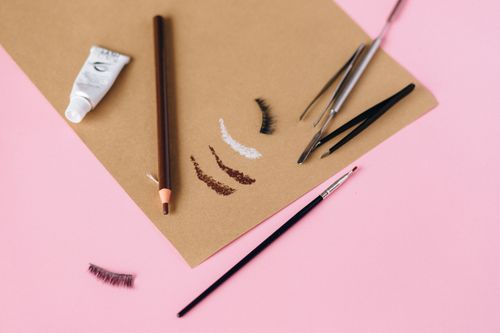 Free A collection of eyebrow makeup tools and cosmetics arranged on a pink surface for beauty styling. Stock Photo