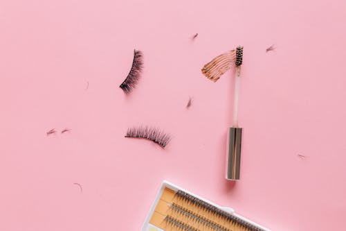 Eyelashes and Mascara Brush on a Pink Surface 