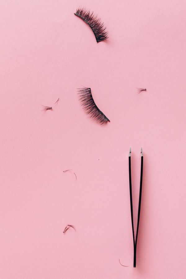 Lash strips and tweezers on a pink surface