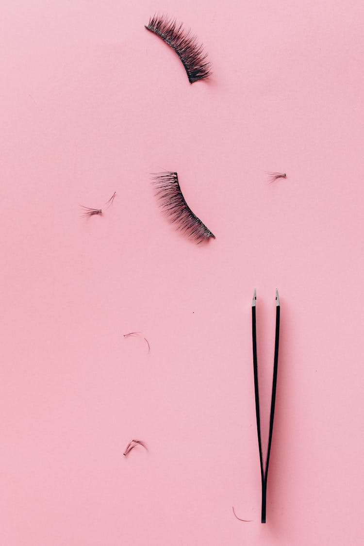 False Eyelashes Beside The Tweezers On Pink Surface