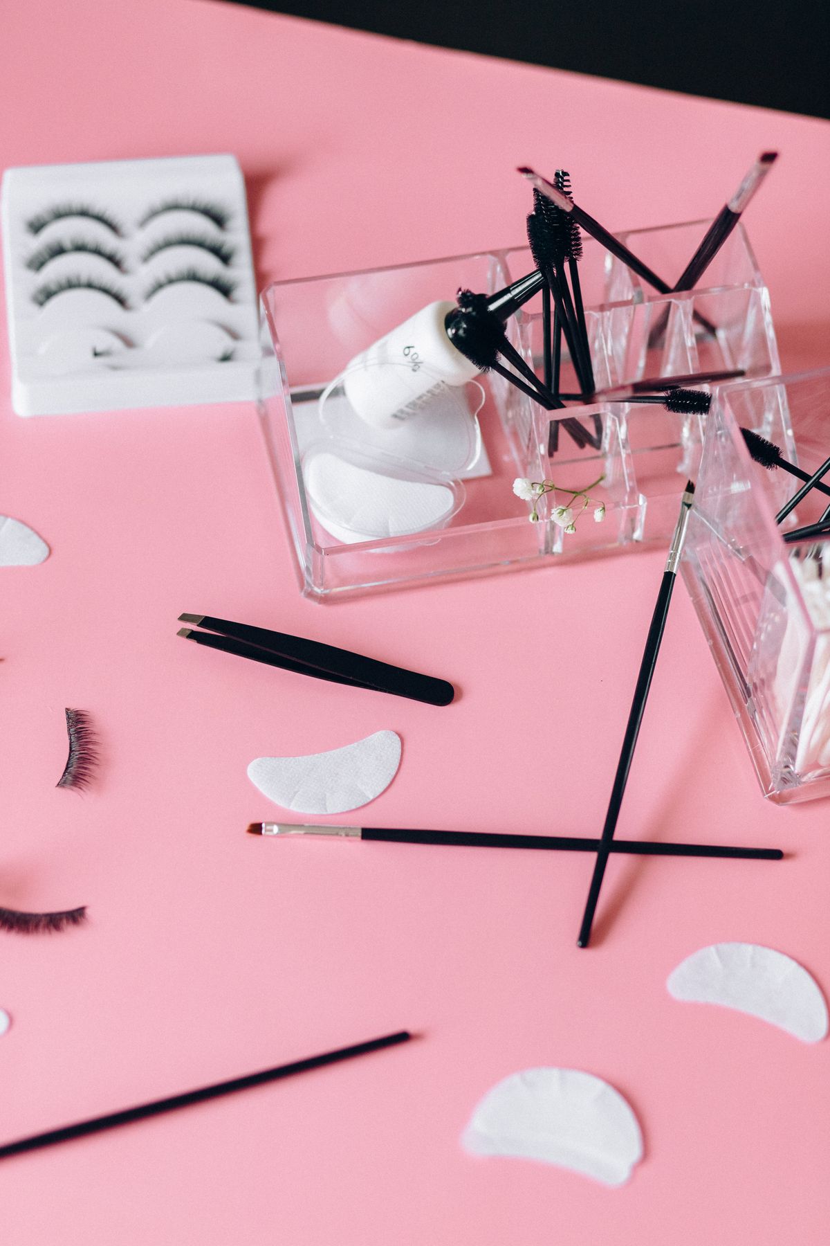 Accesorios de pestañas sobre fondo rosa