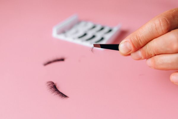 Single lash held in tweezers on pink