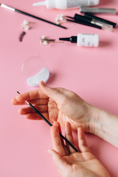 Free A Person Holding a Make-up Brush while Hands are Resting on a Pink Surface Stock Photo