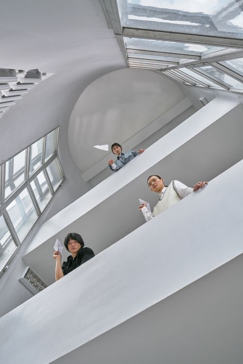 Free Three adults engage in a high-rise paper plane activity emphasizing teamwork and creativity. Stock Photo