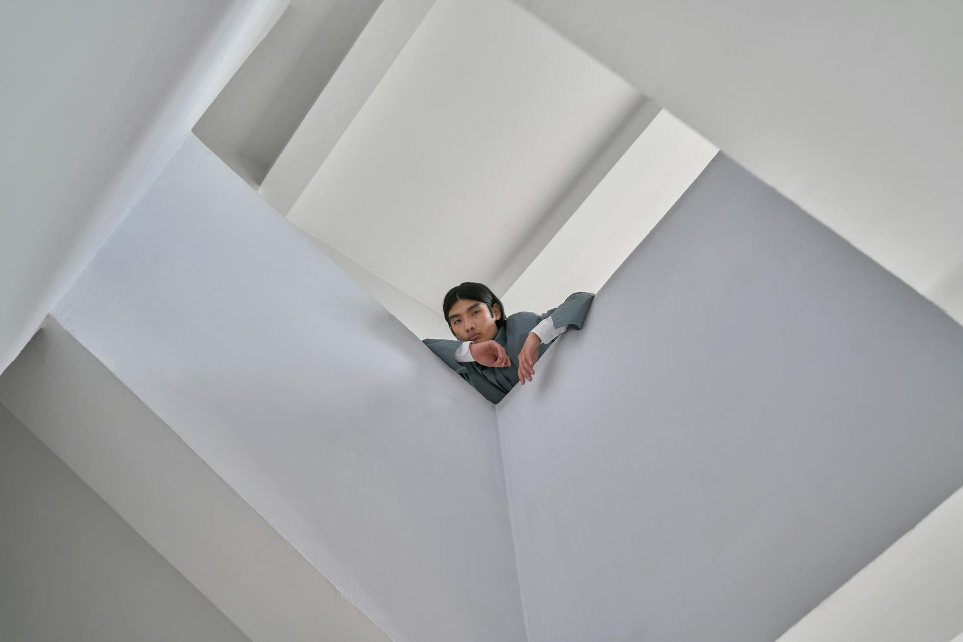 Asian man in modern architecture space taken from low angle emphasizing geometric design.