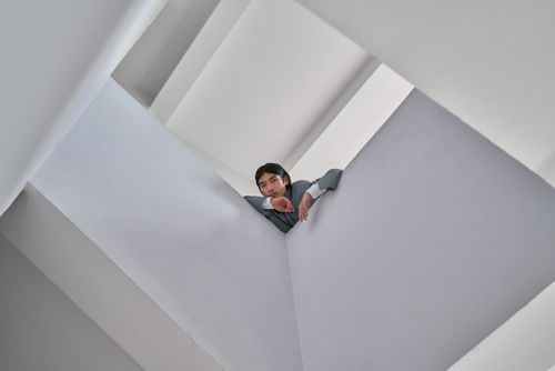 Free Asian man in modern architecture space taken from low angle emphasizing geometric design. Stock Photo