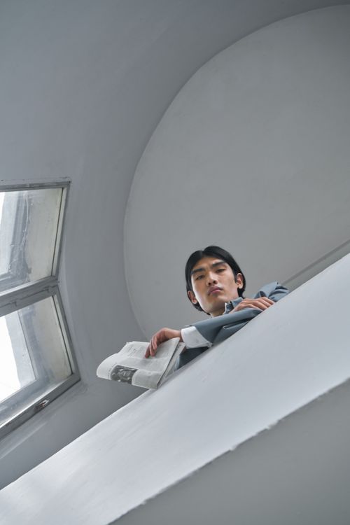 Free Elegant low angle shot of a pensive man holding a newspaper, dressed in blue indoors. Stock Photo
