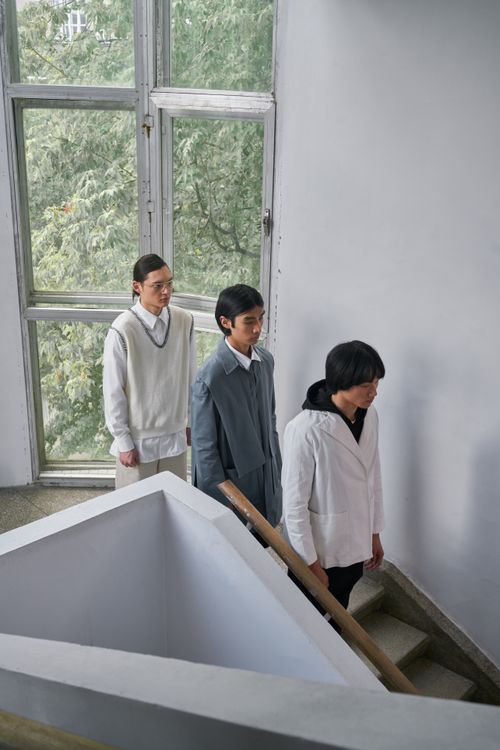 Free Three men in formal attire walking down a staircase inside a modern building with large windows. Stock Photo
