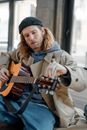 A Man Wearing Black Beanie Adjusting the Tone of the Guitar
