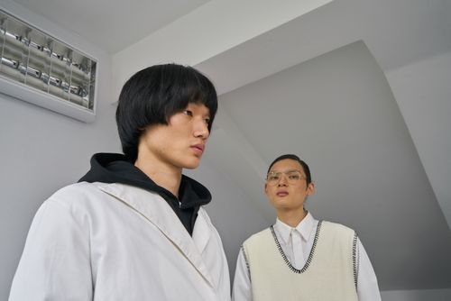 Free Two stylish Asian male models posing indoors with a minimalist fashion aesthetic. Stock Photo