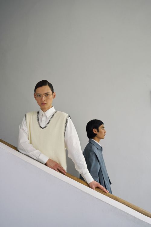 Free Two men in stylish outfits posing on a minimalist staircase indoors. Stock Photo