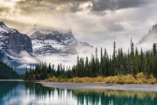Stunning view of snow-covered mountains reflecting in a serene river in Alberta's winter landscape.